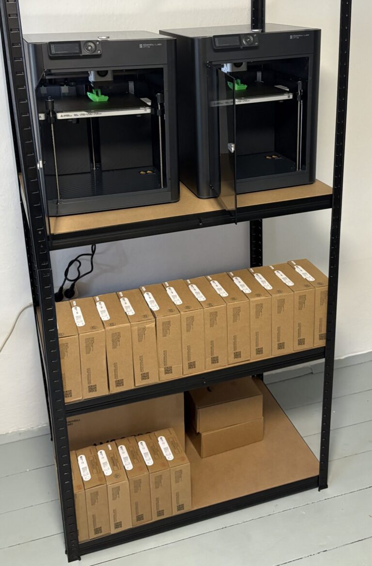 Polička s 3D tiskárnami a materiály pro 3D tisk